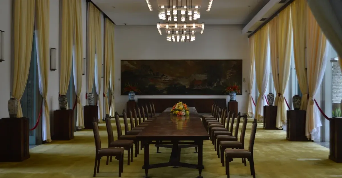 Besloten diner in een lange Amsterdamse ruimte met centrale tafel, plafondornamenten, paneeldetails en warm gedempt licht