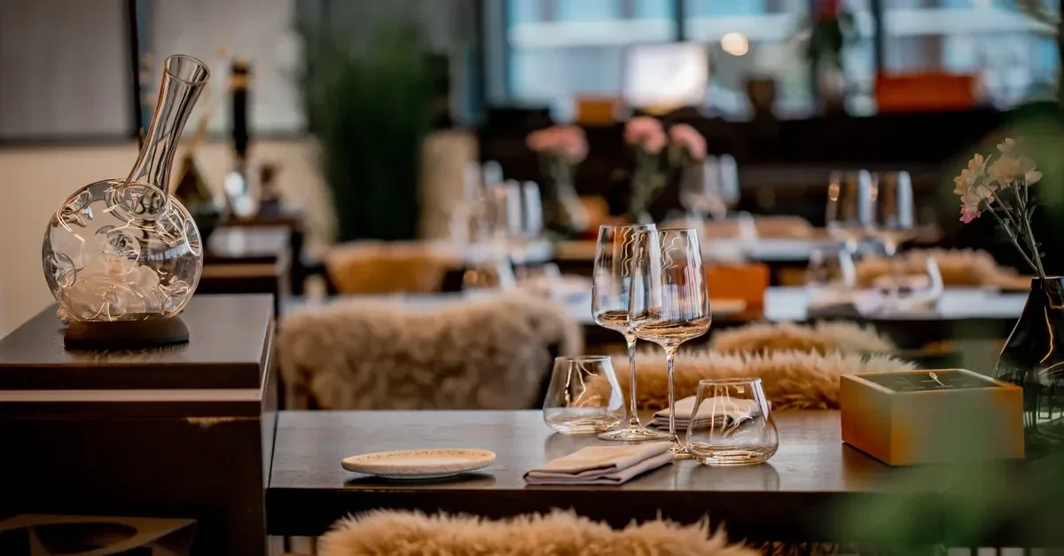 Intieme Amsterdamse dineravond aan een elegant gedekte tafel, donker hout, warm messing, kaarslicht en diepe schaduwen